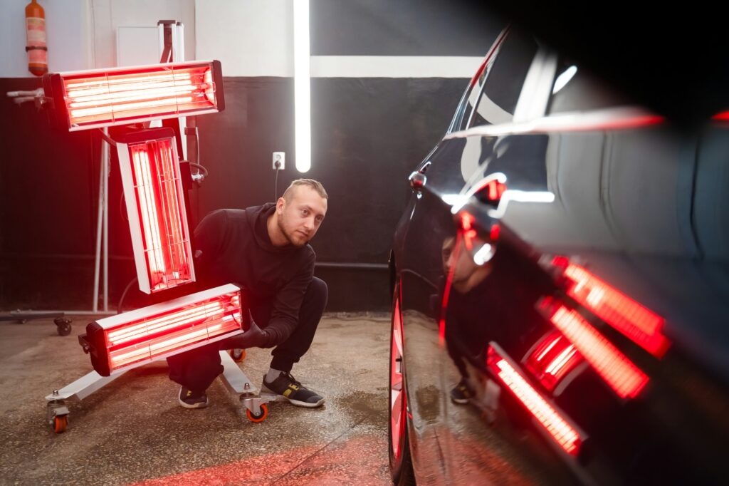 Detailing worker with infrared lamps near the car. Car detailing concept